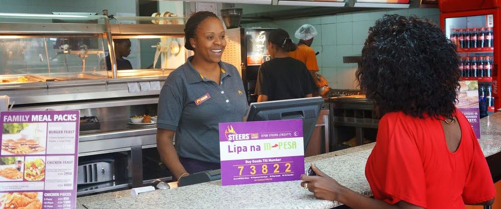 Photo showing a customer and M-PESA payment sign in a Steers fast food restaurant in Kenya.